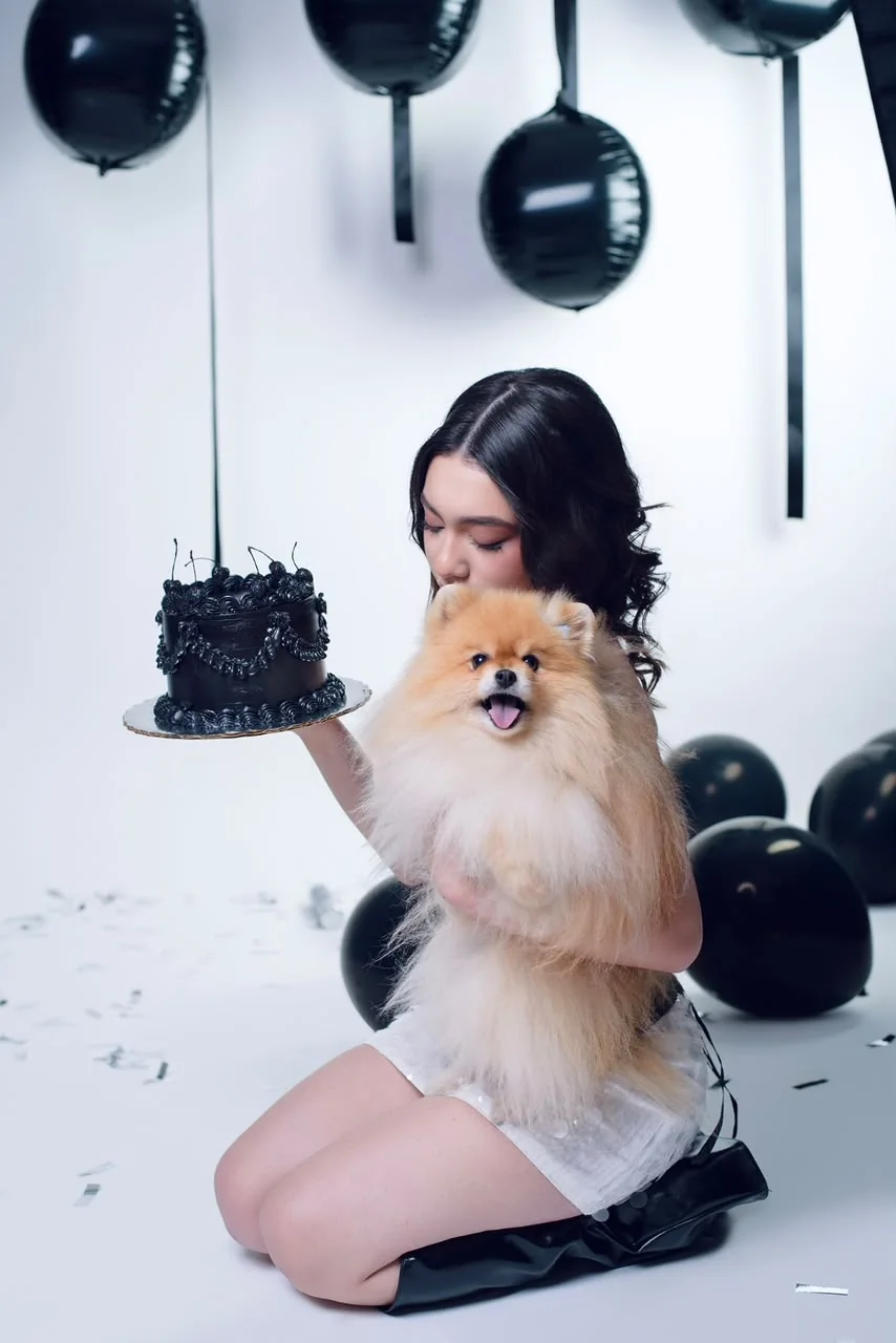 Valentina con su perrito y un pastel negro