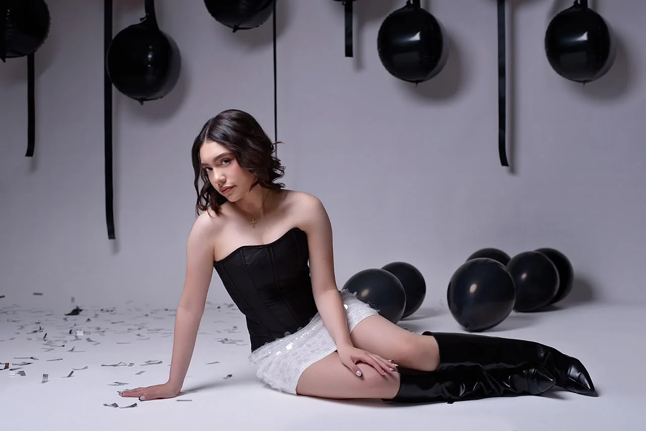 Valentina sentada entre globos negros